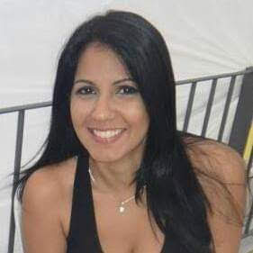 Mulher de cabelos pretos longos e lisos e olhos pretos sorrindo para a foto